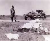 A GI standing near the body of a German soldier who was killed on the road near Chambois France. By the roadside a German multiple rocket launcher MRL 15 cm Panzerwerfer 42 Sd.Kfz.4- 1 from cuting a gi