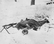 The body of a dead German soldier from the 416th Infantry Division of 7th Army (Wehrmacht) lays next to his MG 42 (Maschinengewehr 42) recoil-operated air-cooled light machine gun in the snow following an attack on troops of the US 94th Infantry Division, from 42 15 32