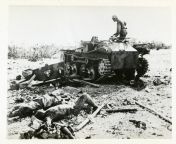 A GI stands on a damaged Japanese tank and looks down on the bodies of dead Japanese soldiers. Philippines. 1945 from 12 yarsi gi