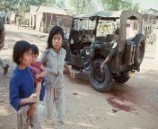 Two young girls, one with an infant, run past a jeep where a South Vietnamese soldier is slumped dead as street fighting continues against Viet Cong forces in Da Nang, S. Vietnam. 30 Jan 1968 from nang ying hom xd